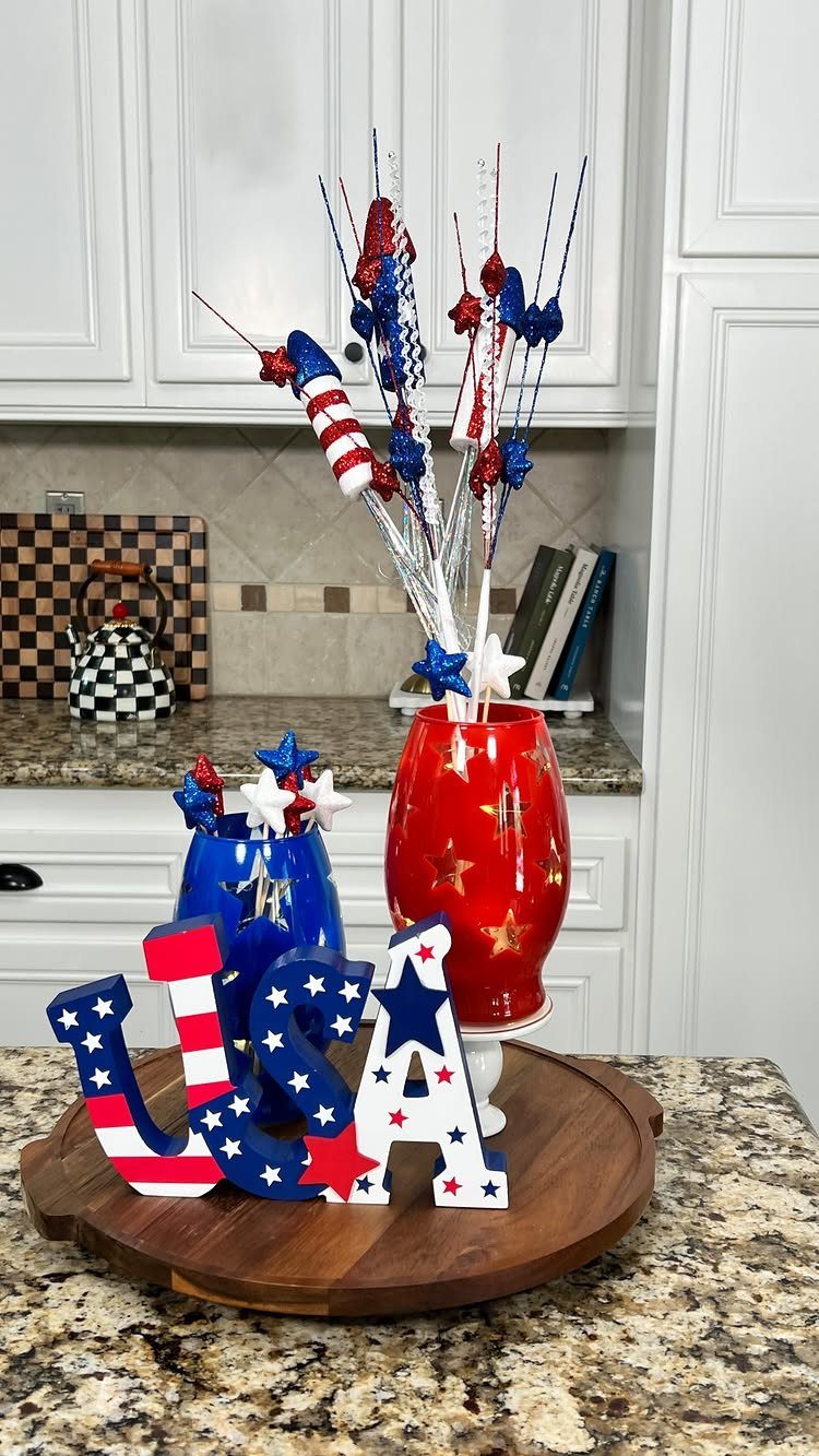 Patriotic table decor with USA letters, red vase, and blue star containers.