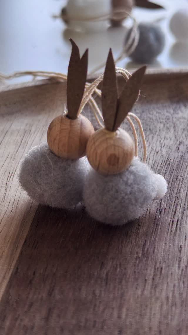Two small bunny gnomes made from grey felt, wooden beads, and cardboard ears.