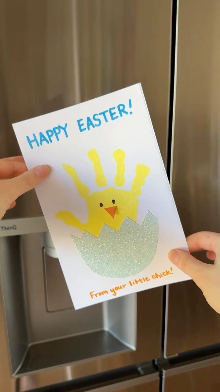 Handmade Easter card with a yellow handprint chick hatching from a glittery eggshell.