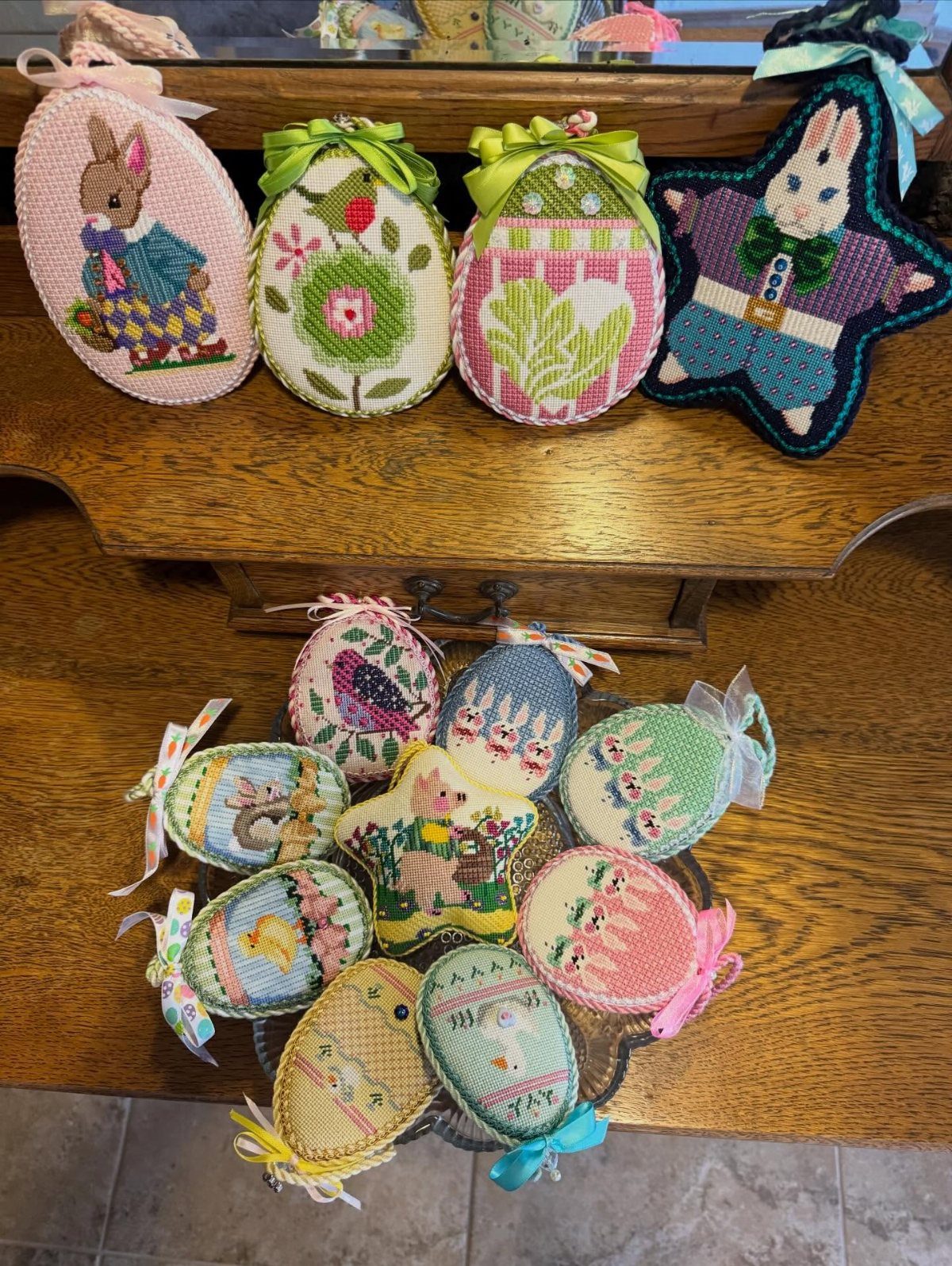 Cross-stitched Easter ornaments shaped like eggs and bunnies on a wooden table.