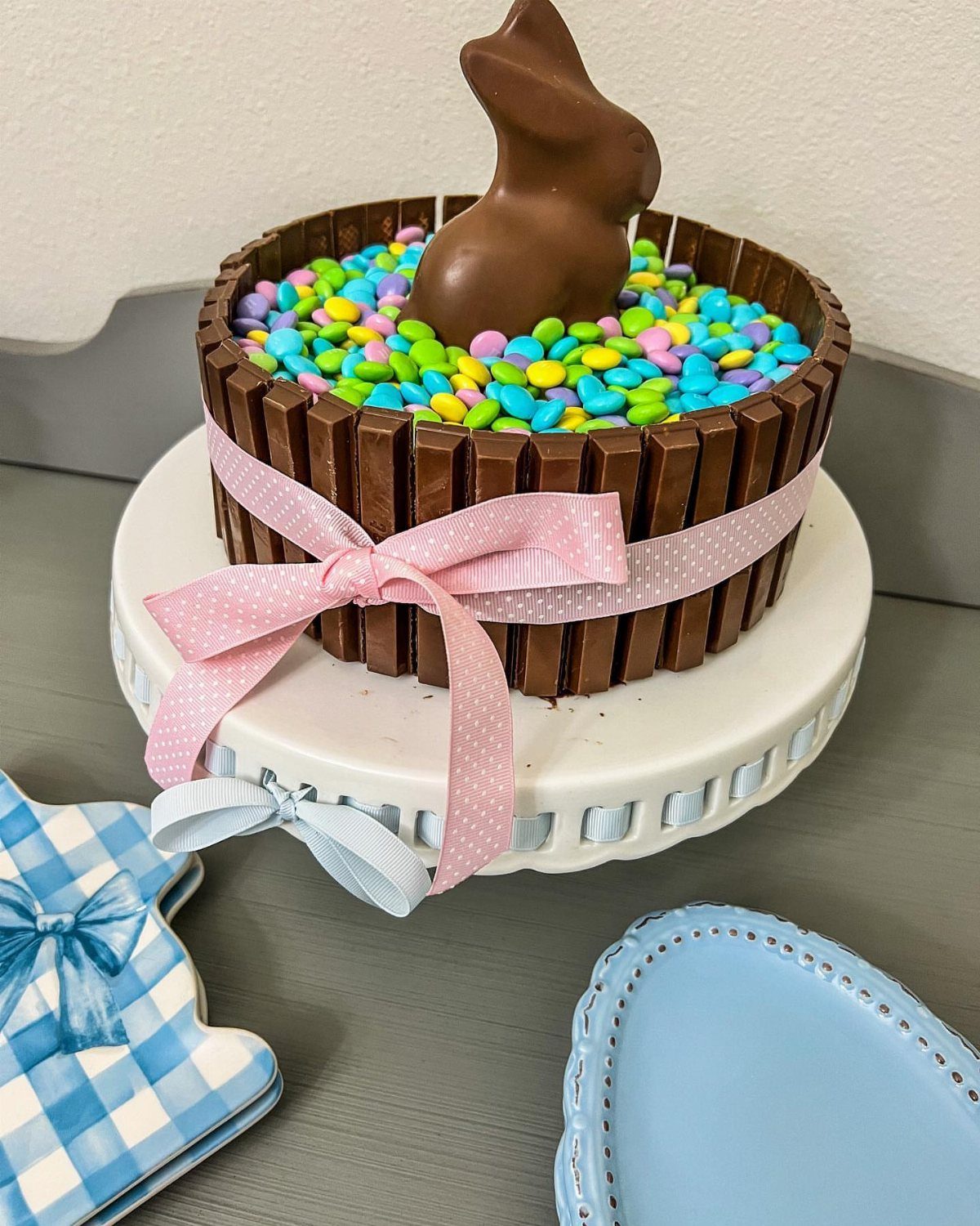 Easter bunny cake decorated with chocolate bars, colorful candy eggs, and a chocolate bunny.