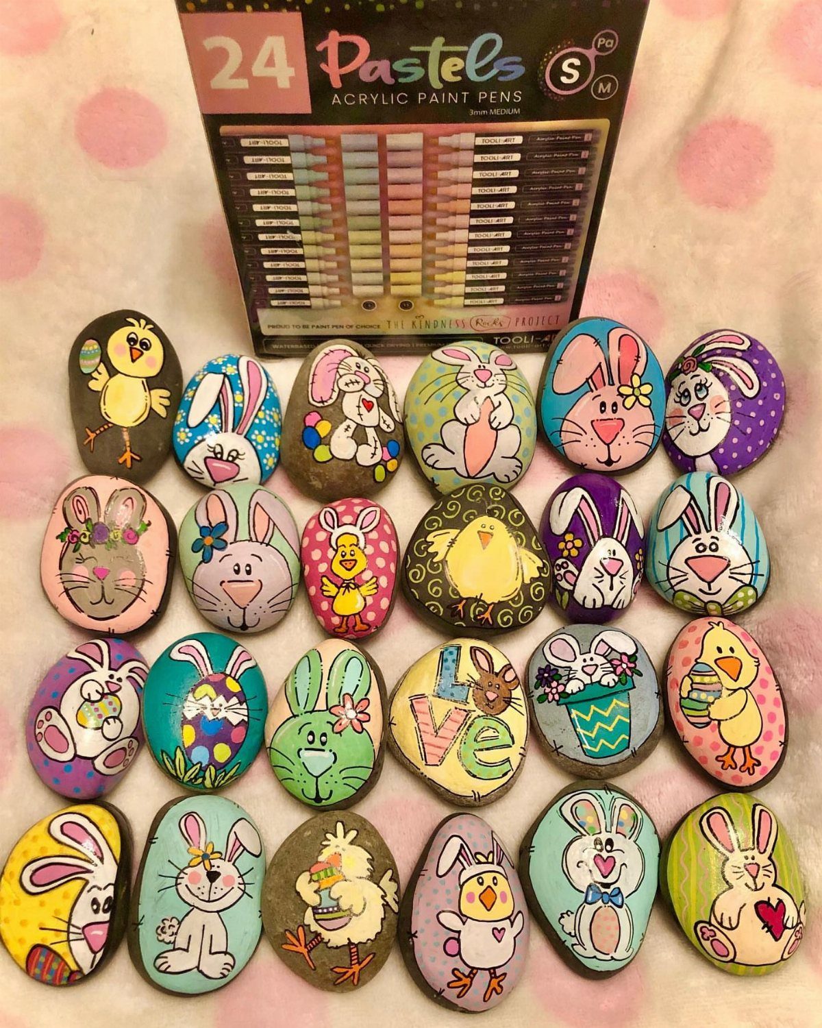 Painted rocks featuring colorful Easter bunnies and chicks next to acrylic paint pens.