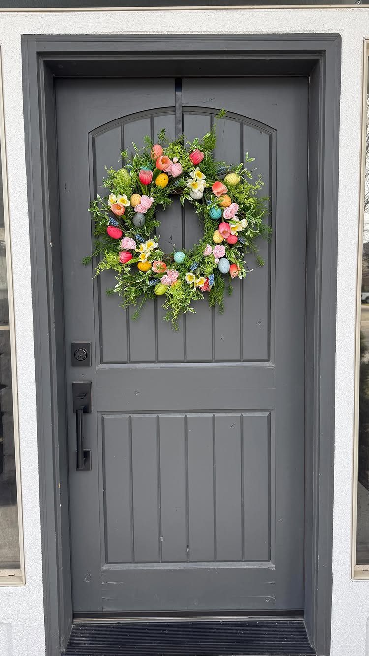Easter egg wreath with colorful eggs and green foliage on a grey door