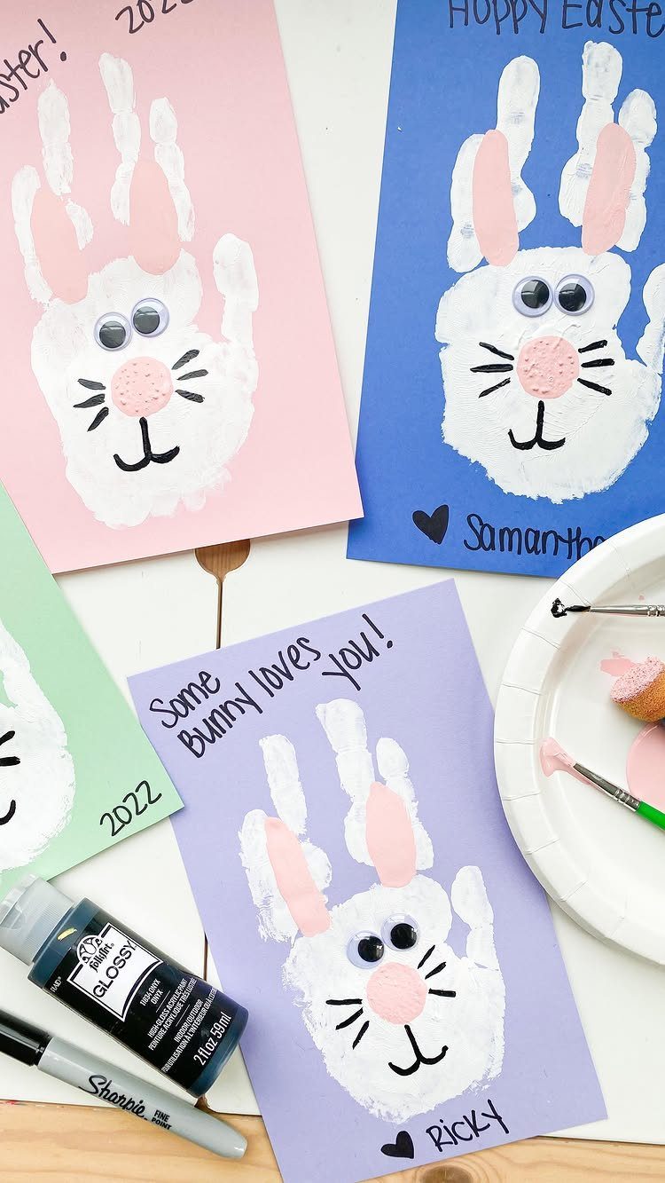 Handprint bunny paintings on colorful cards with googly eyes and pink noses.
