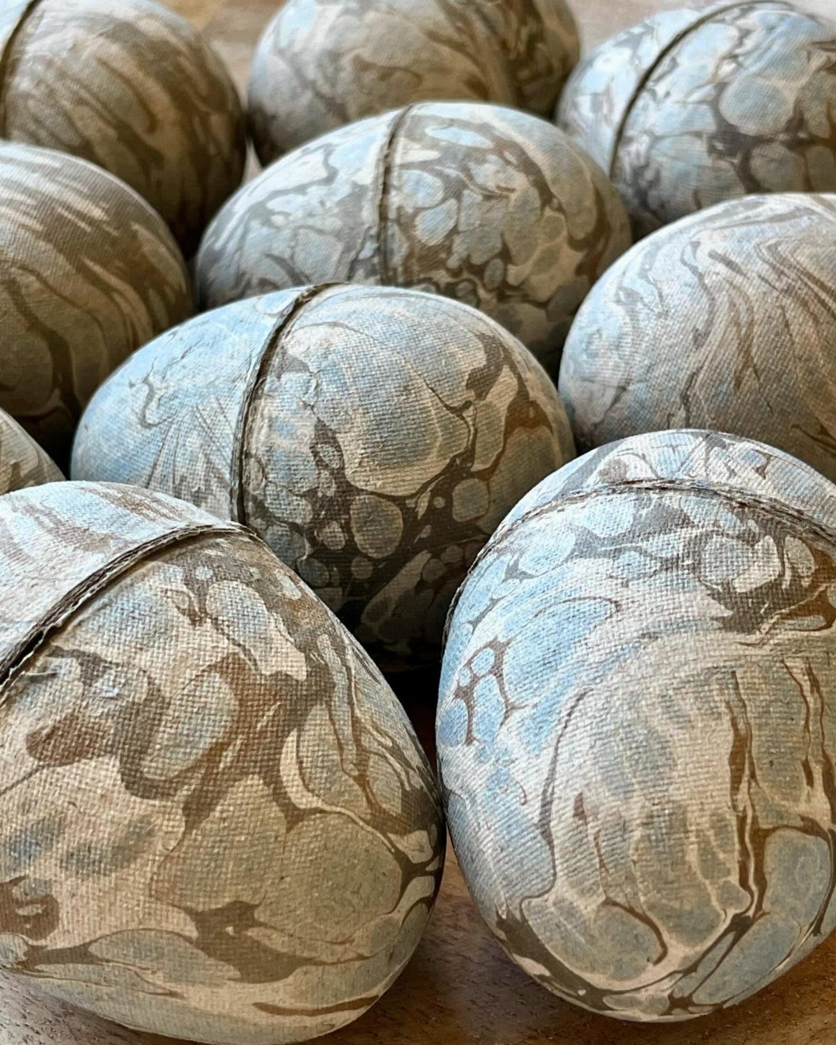 Marbled paper eggs with brown and blue swirls arranged in a group.