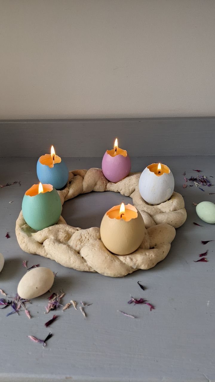 Colorful egg-shaped candle holders resting on a braided salt dough wreath with petals.