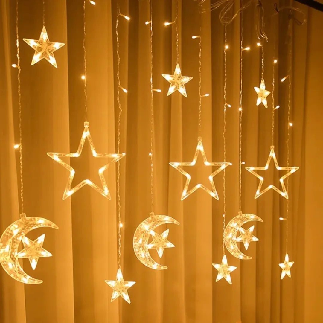 Crescent moon and star LED string lights hanging against beige curtains.