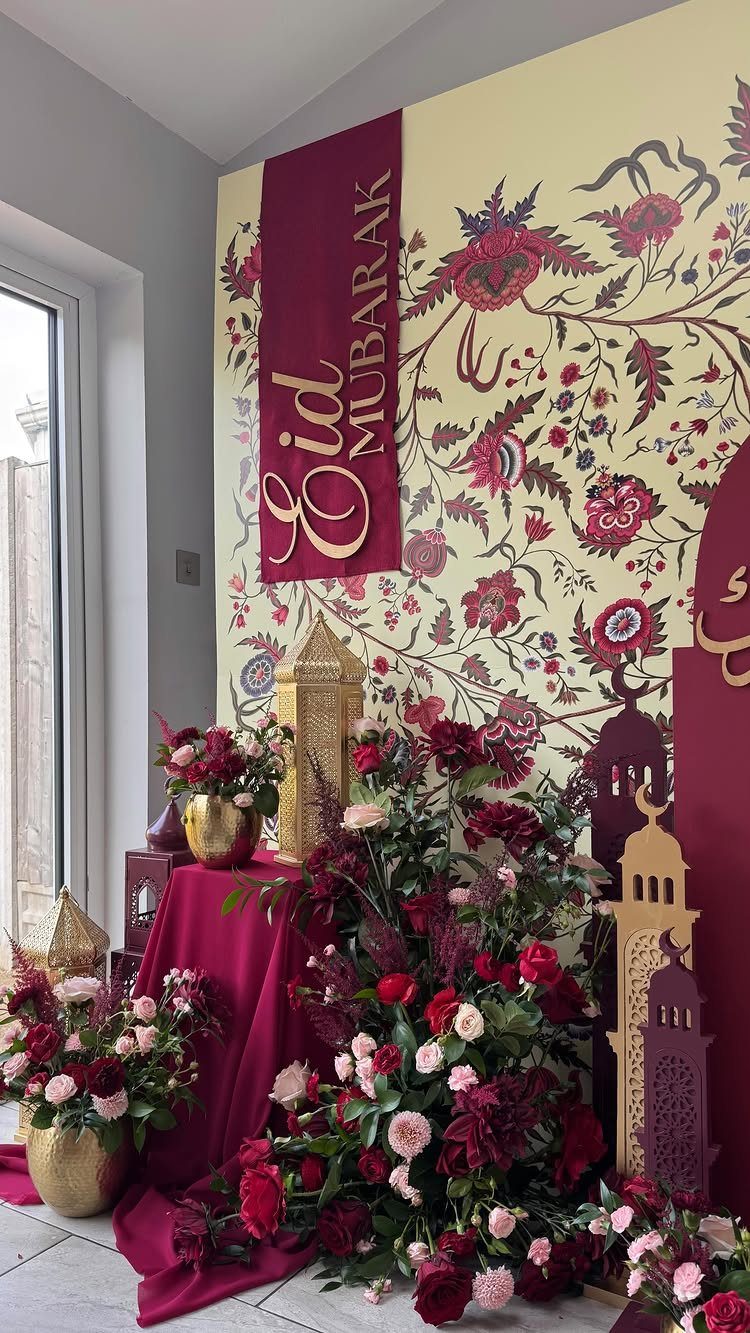 Festive Eid Mubarak setup with red roses, gold lanterns, and burgundy fabric decorations.