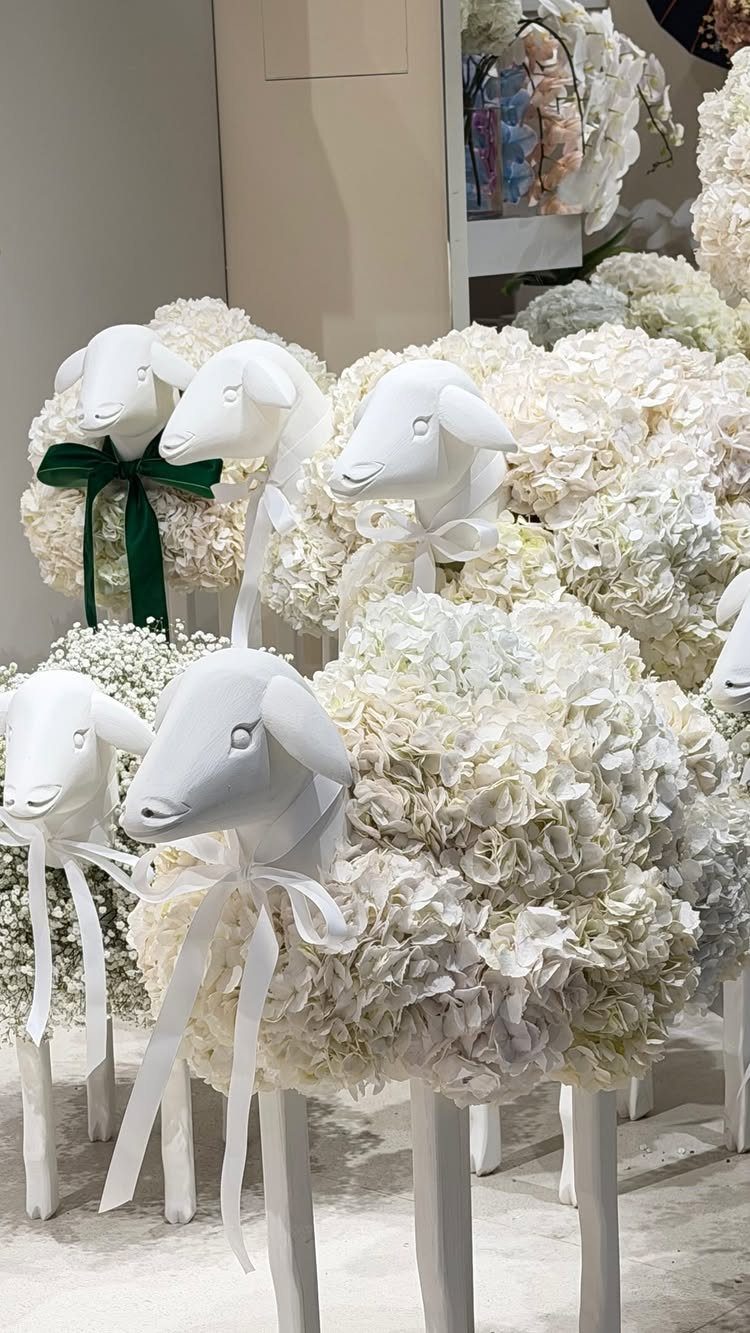 Stylized sheep figures crafted from white floral petals and smooth white materials.