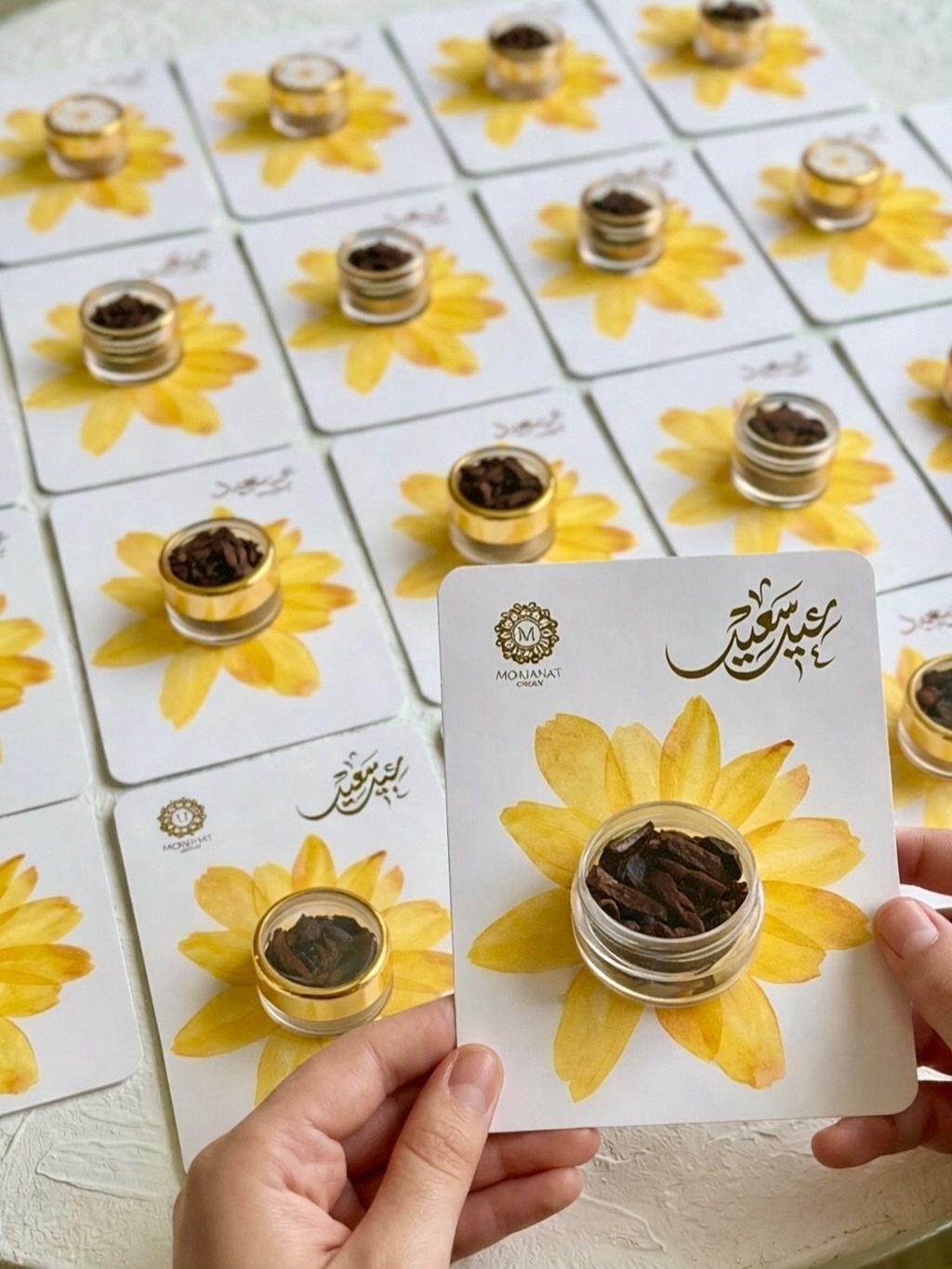 Small favor jars embedded in flower-themed cards with Arabic calligraphy for Eid celebrations.