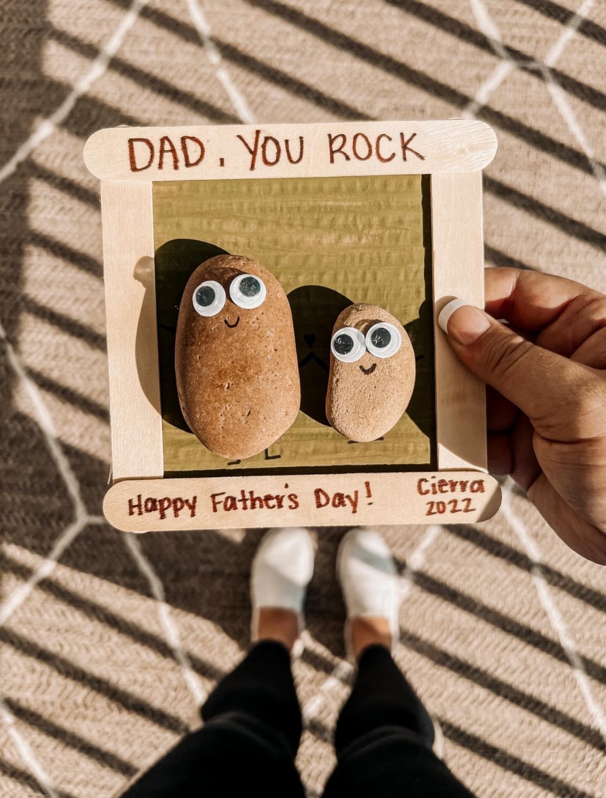 Two brown stones with googly eyes inside a wooden Father's Day frame