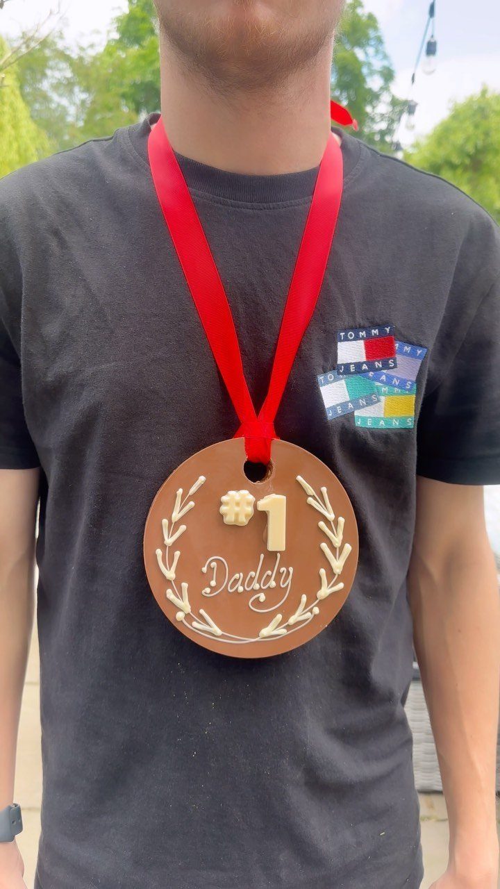 Handmade brown Father's Day medal with red ribbon worn by a man