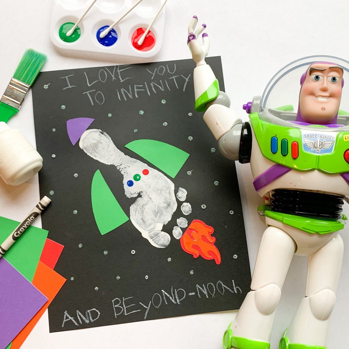 Footprint rocket craft on black paper next to a Buzz Lightyear action figure