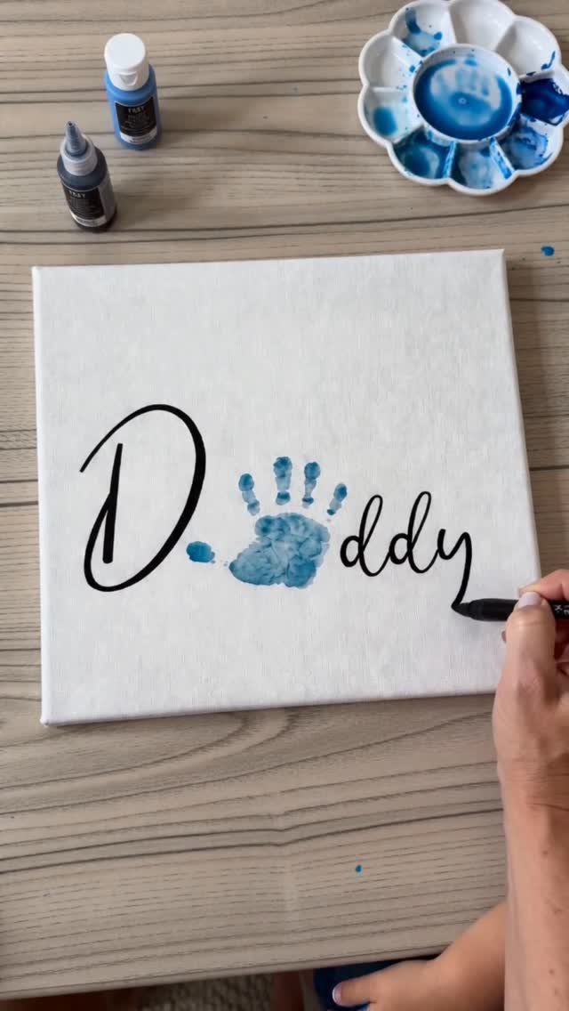 White canvas with a blue child's handprint and the word Daddy written in black