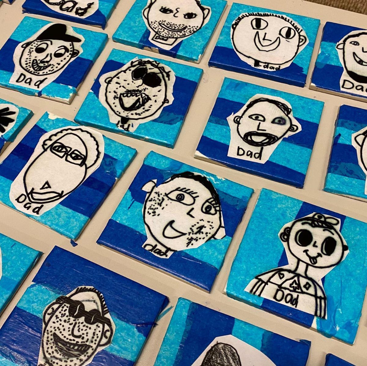 Handmade blue striped coasters featuring children's drawings of fathers' faces and the word Dad.