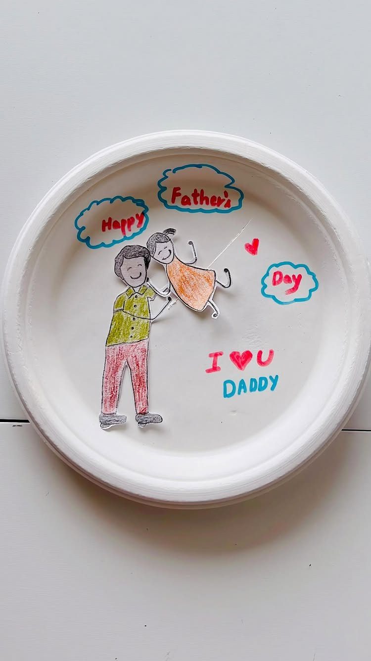 White paper plate craft with a drawing of a father and daughter hugging.