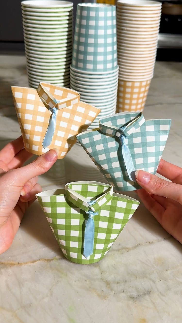 Gingham patterned paper cups decorated as collared shirts with small blue ribbon ties.