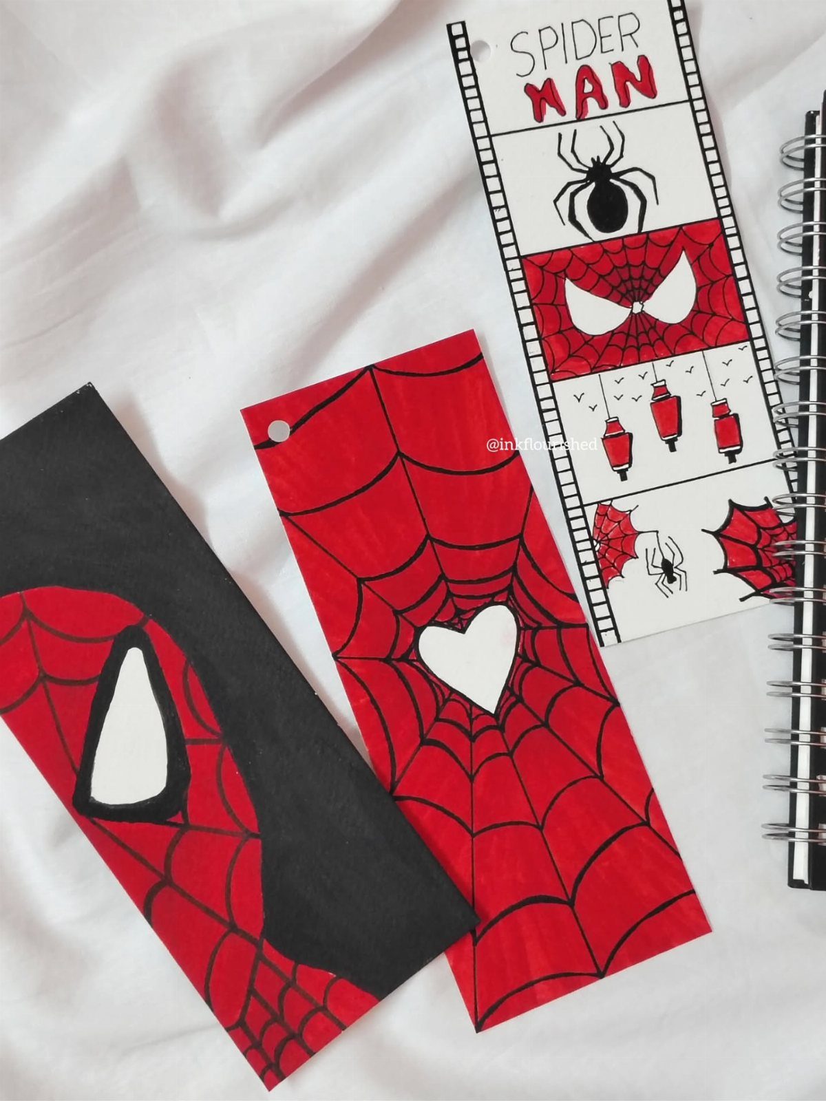 Three handmade Spider-Man bookmarks featuring red webs and masks on white fabric.