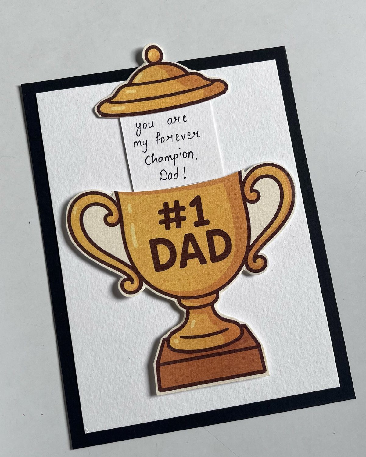 Trophy-shaped Father's Day card with #1 Dad text and a handwritten note.