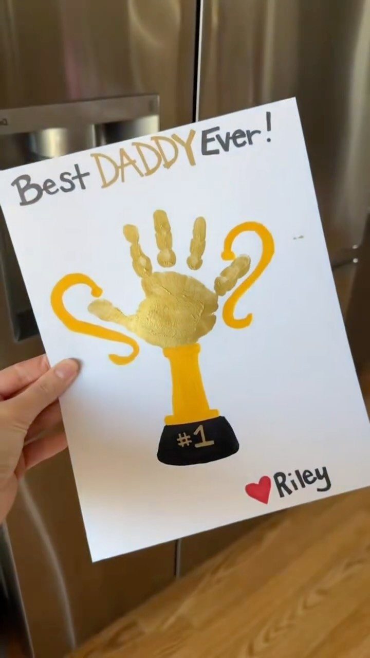 Gold handprint painted as a trophy on white paper for Father's Day.