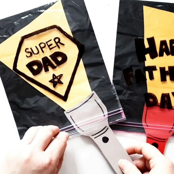 Hands using a paper flashlight to reveal a Super Dad superhero card