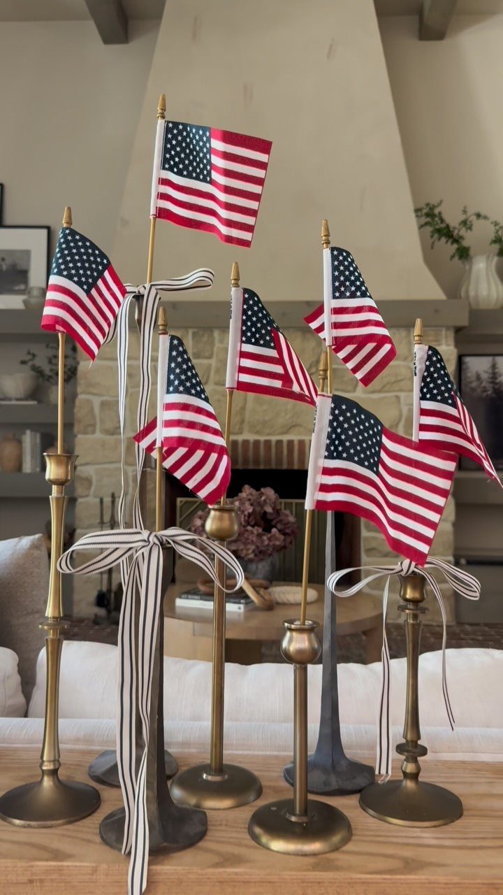 Small American flags displayed on gold candle holders with striped ribbons in a home.