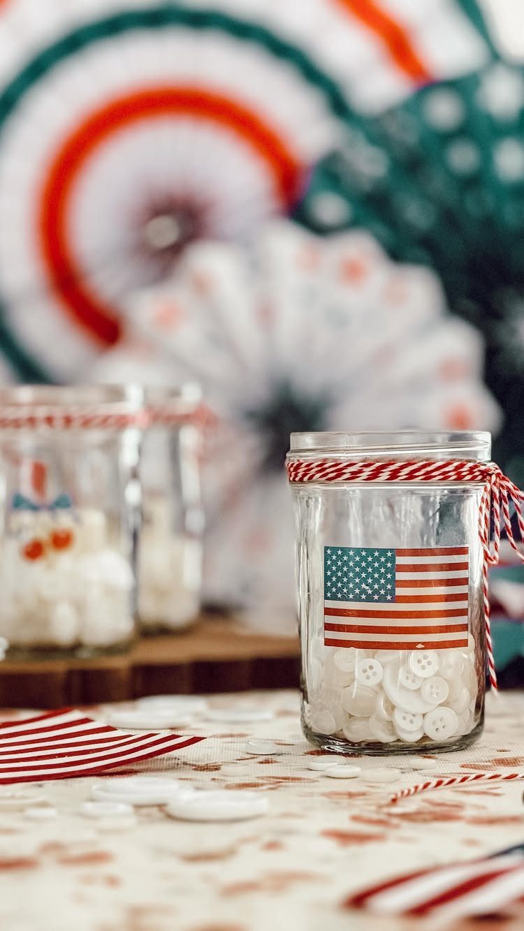 Glass jars filled with white buttons decorated with American flags and striped twine.