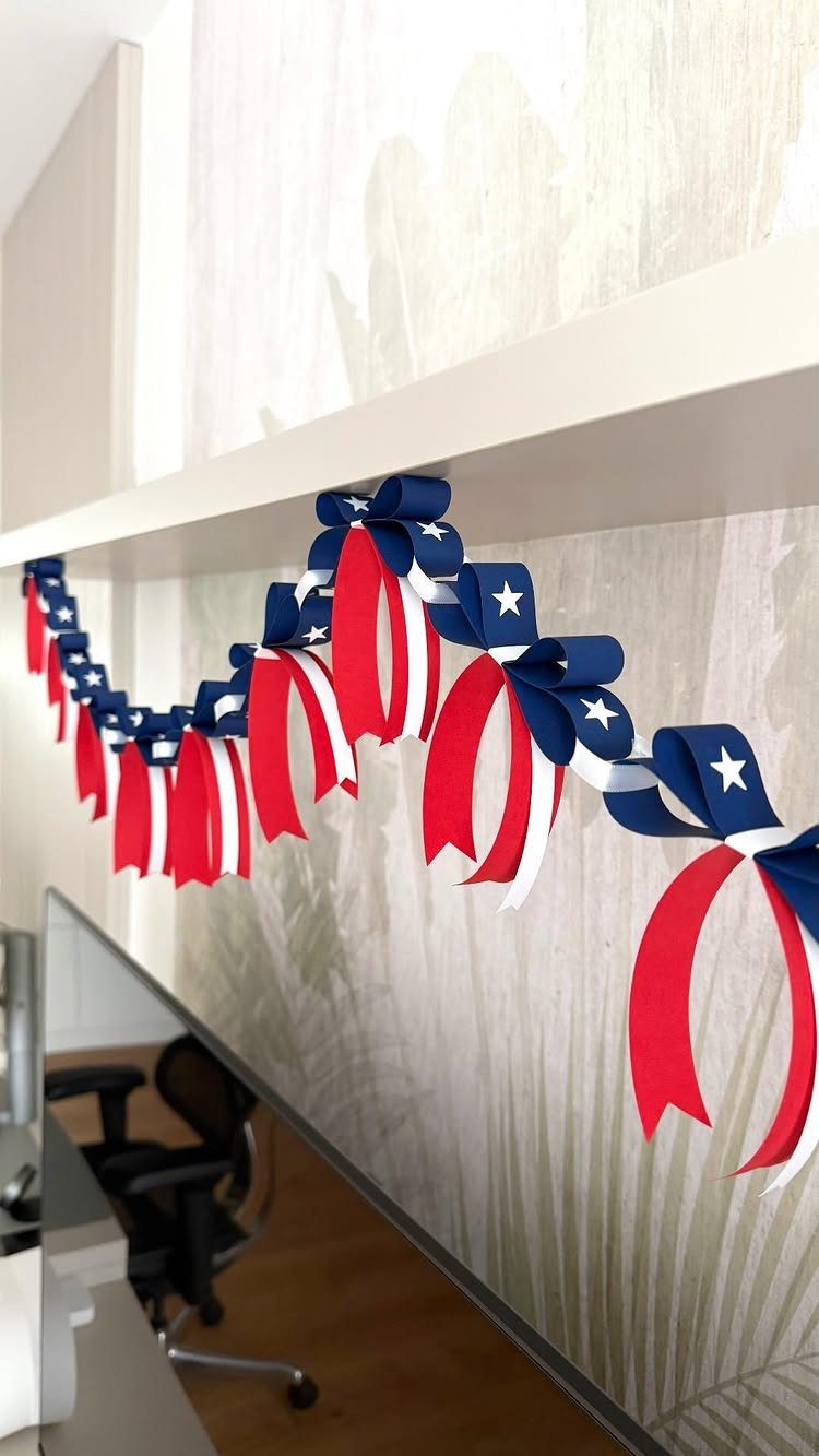 Red, white, and blue ribbon garland with stars hanging on a white shelf.