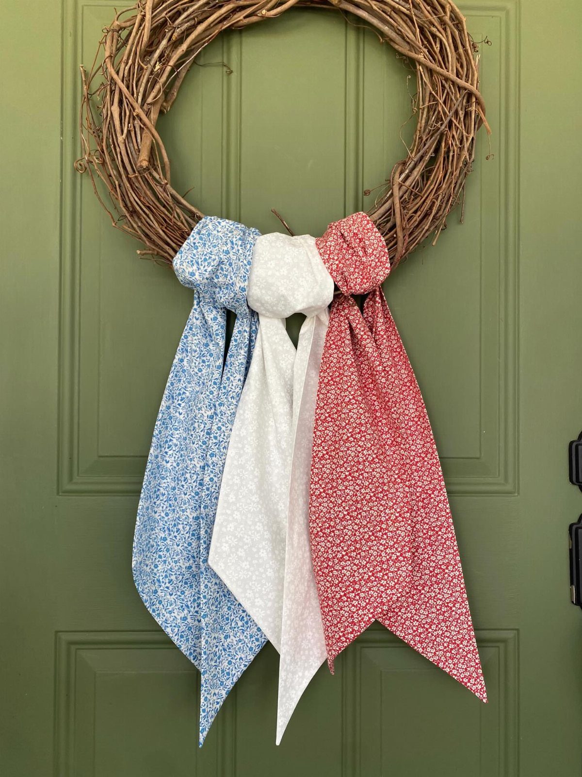 Grapevine wreath on a green door decorated with red, white, and blue bandanas.