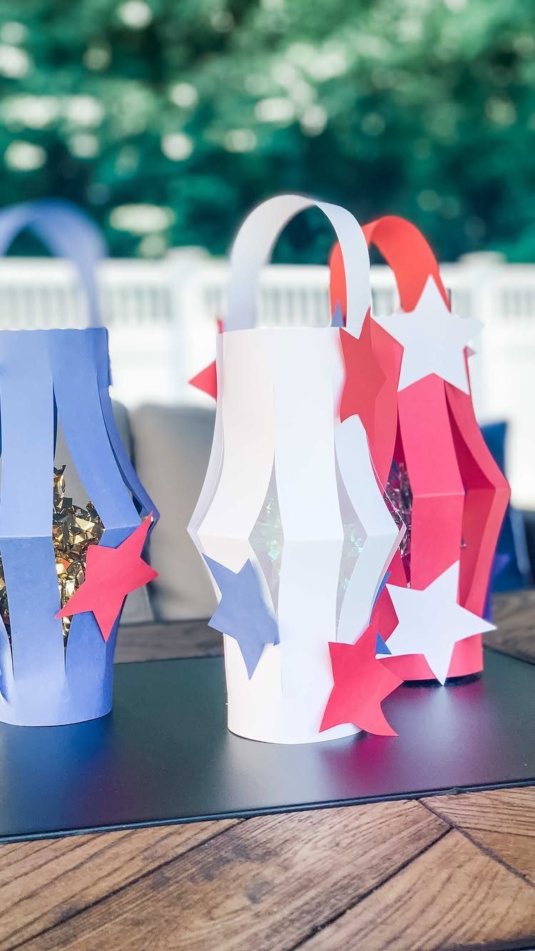Red, white, and blue paper lanterns with star decorations on a wooden table.