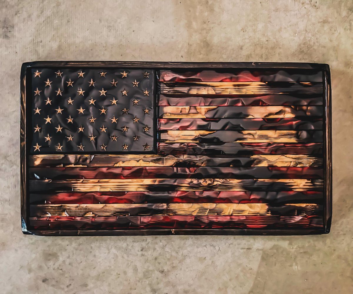 Rustic American flag made from charred wooden planks on a neutral stone background