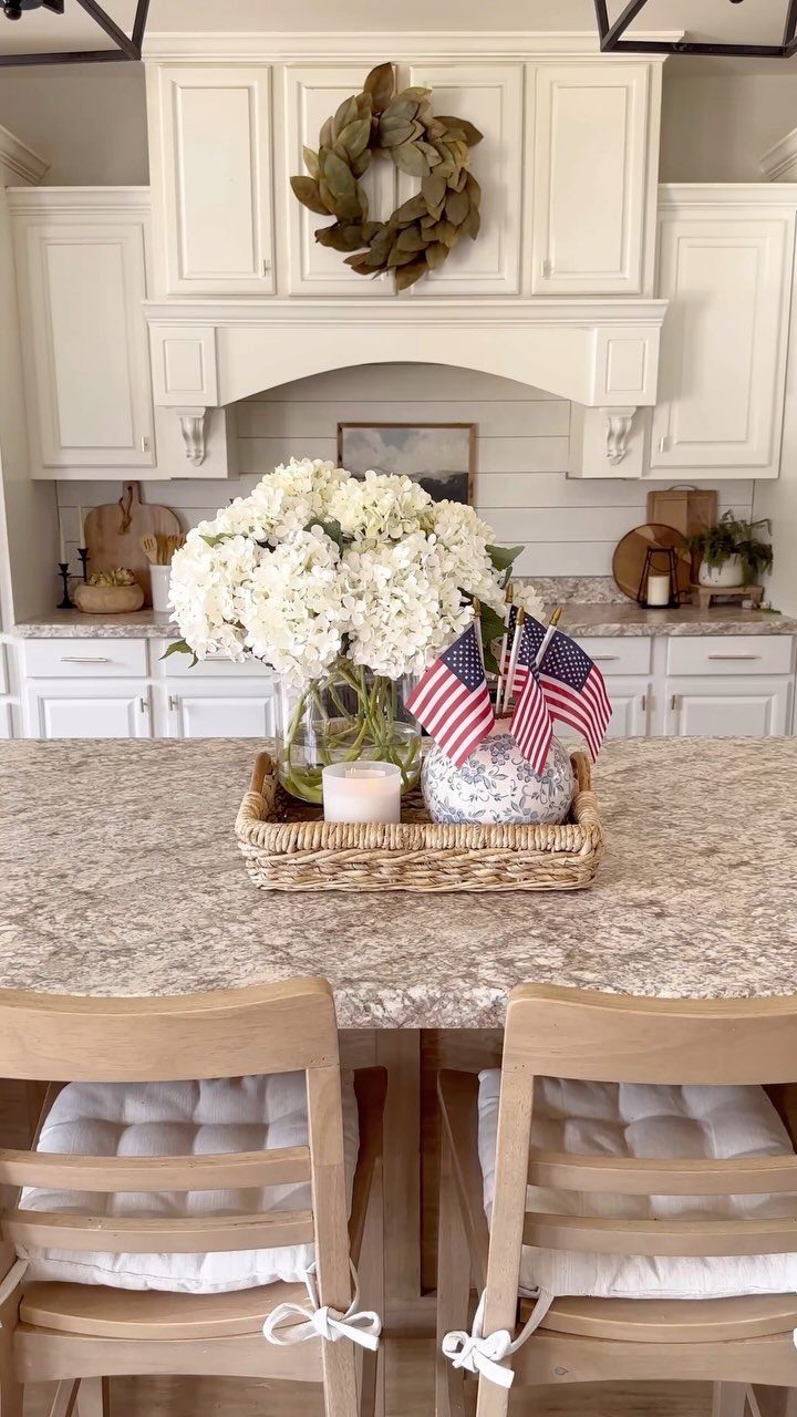 Two small American flags and white hydrangeas in a woven tray on a countertop.