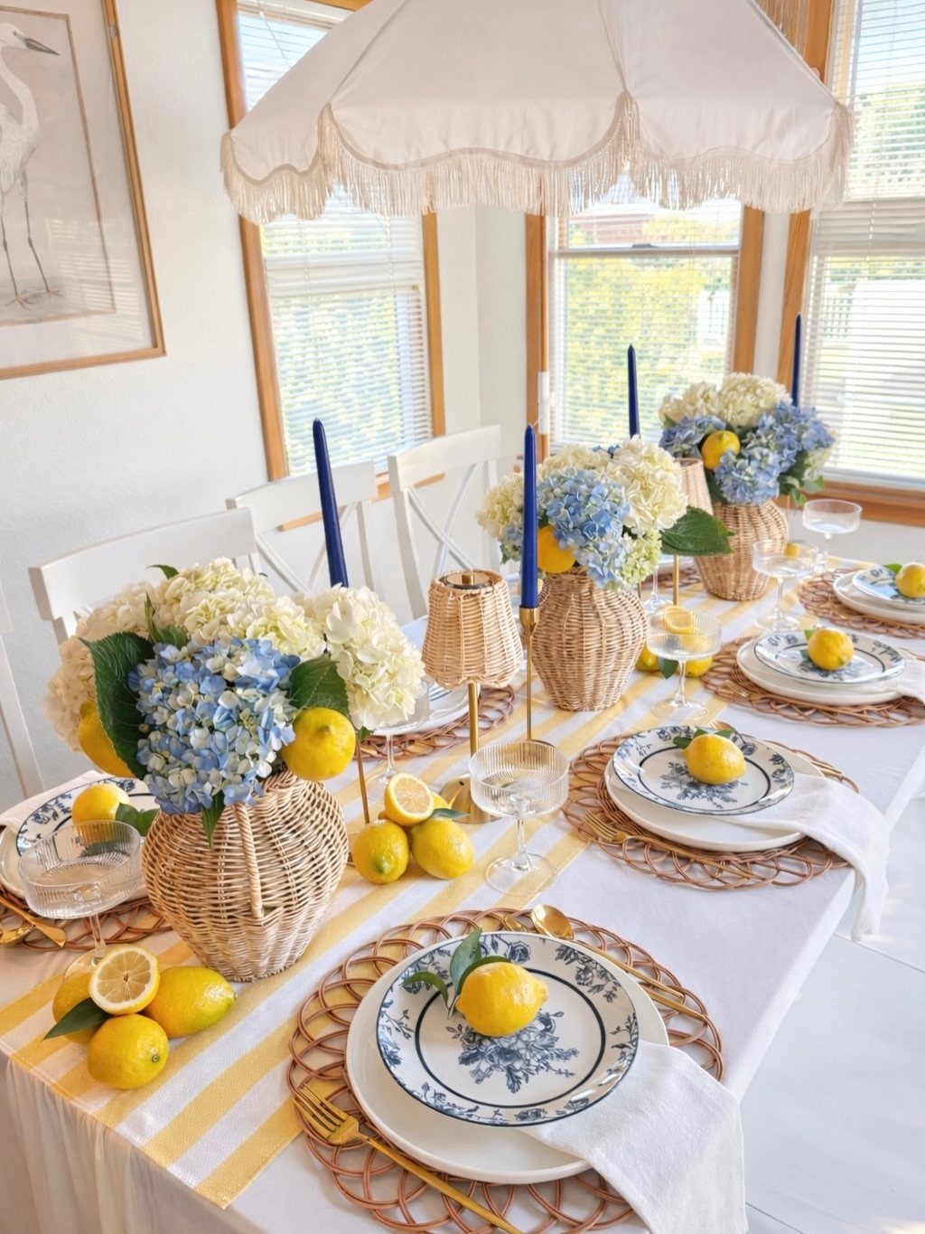 Dining table with blue and white floral plates, wicker chargers, and blue hydrangeas.