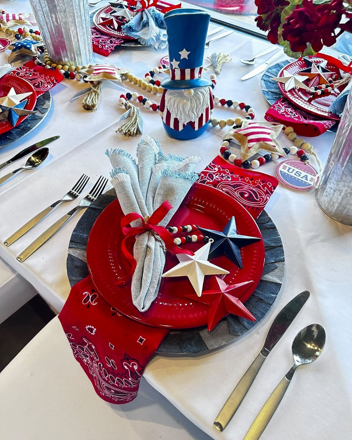 Red plate on a grey charger with patriotic napkins and star decorations.
