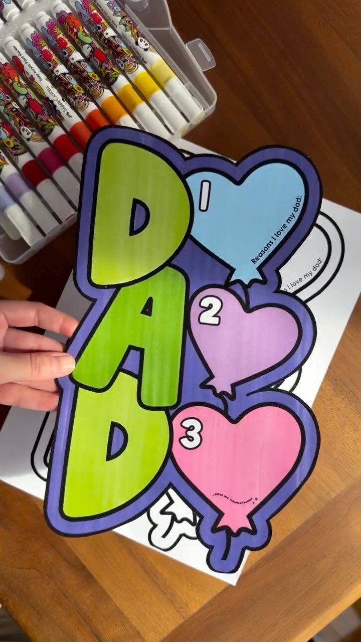Colored Father's Day cutout with 'DAD' and heart balloons held over markers.