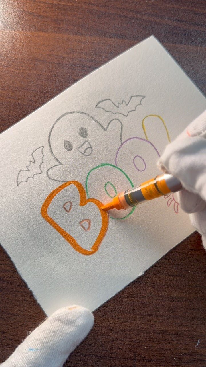 Hand coloring a Halloween page with a ghost and the word BOO.