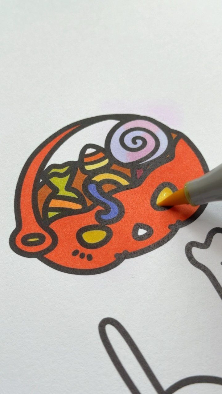 Hand coloring a pumpkin candy bucket with a yellow marker on white paper.
