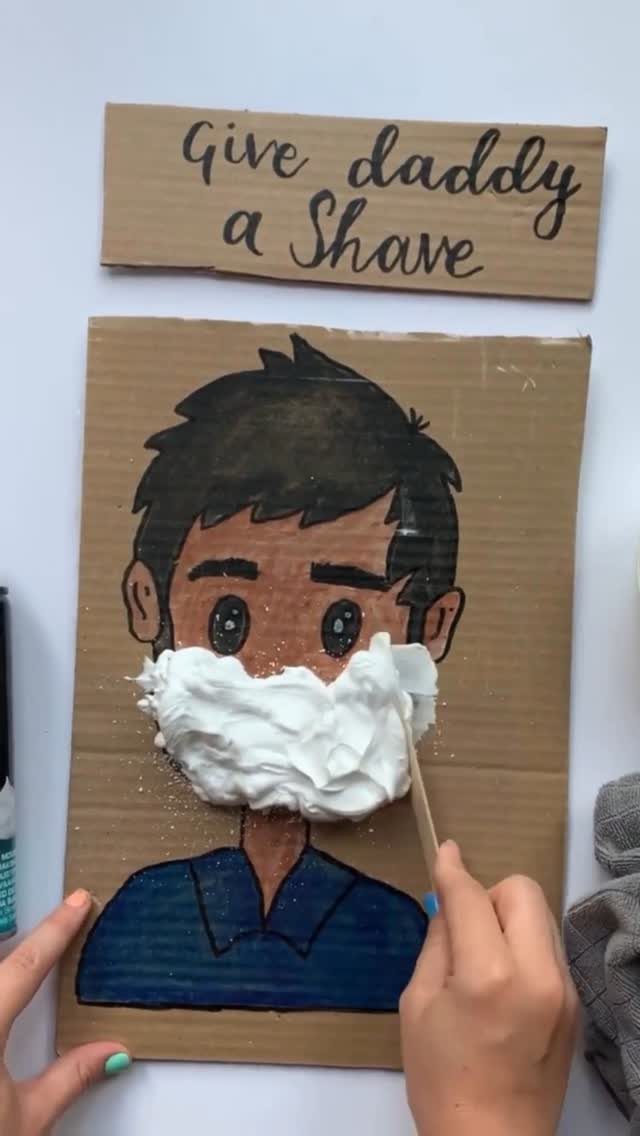 Child spreading shaving cream on a cardboard drawing for a Father's Day craft.