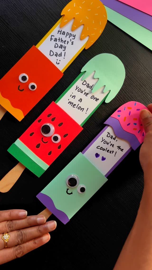 Paper popsicle crafts with googly eyes and Father's Day messages on a black background