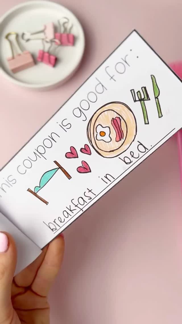 Printed breakfast in bed coupon held by a hand against a pink background