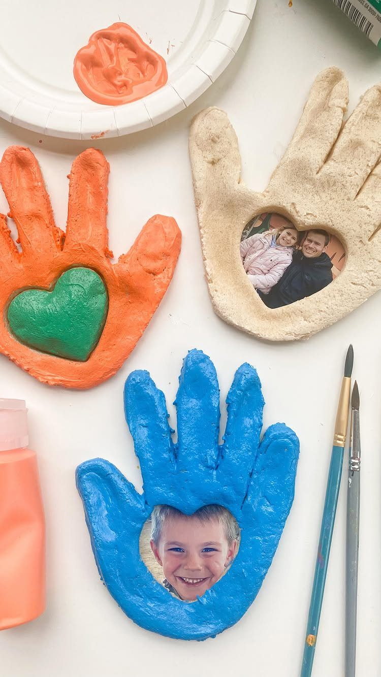 Handprint salt dough frames in orange, blue, and beige with photos and paintbrushes.