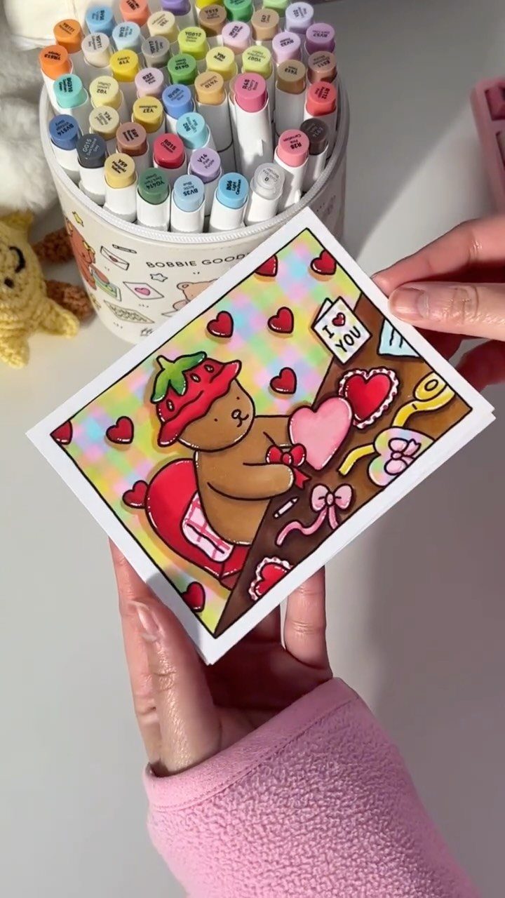 Hand-colored Valentine's Day card featuring a cute bear with a strawberry hat and hearts.