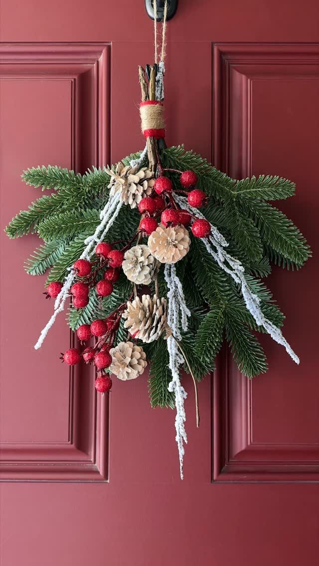 Christmas swag with red berries and pinecones hanging on a red front door