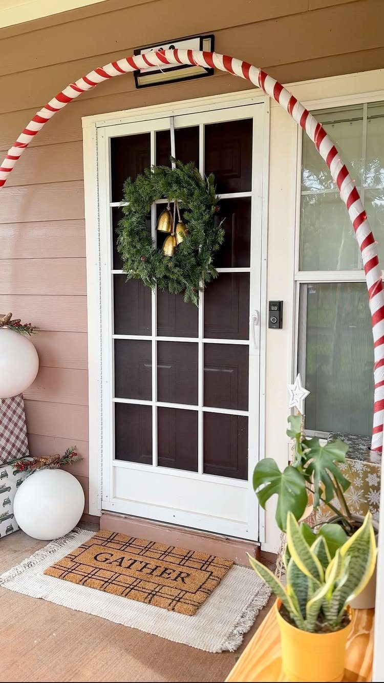 White front door with a candy cane arch and a green holiday wreath.