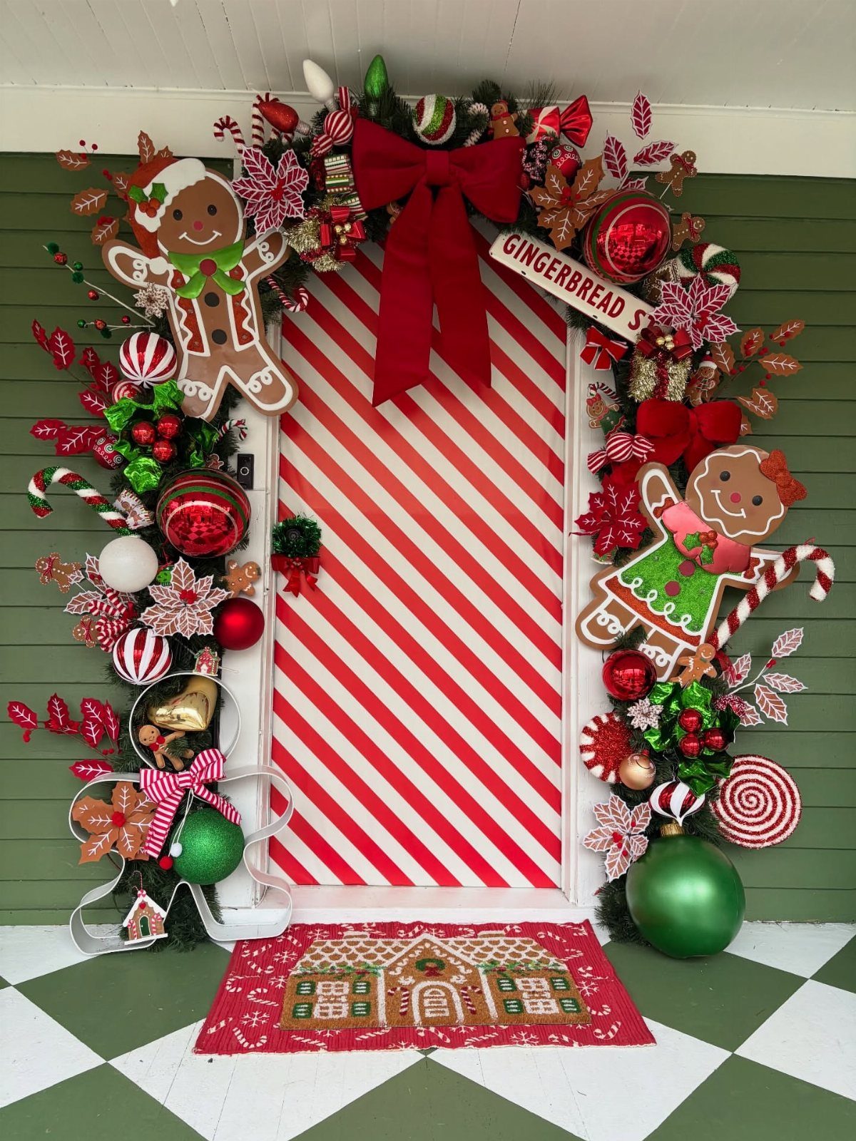 Red and white striped door decorated with gingerbread men, garland, and ornaments.