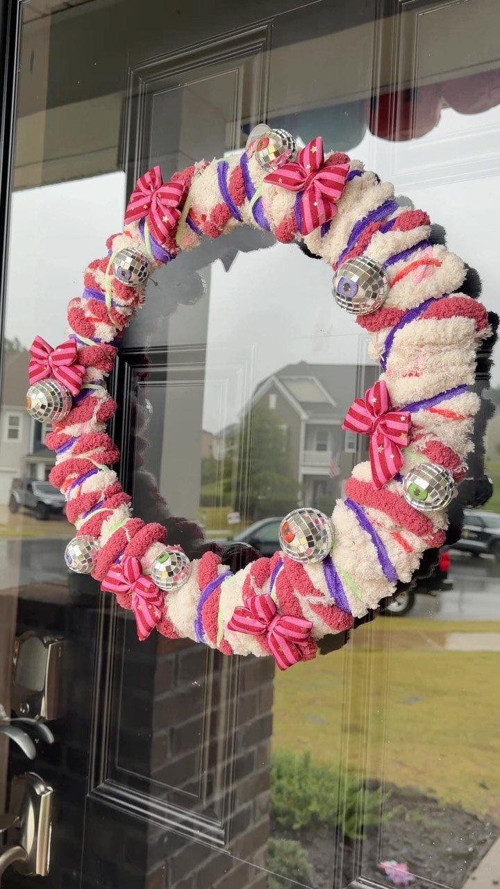 Textured pink and white wreath with silver ornaments on a black front door.