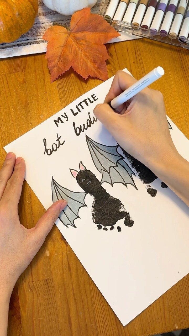 Handprint bat painting on white paper being decorated with a white marker.