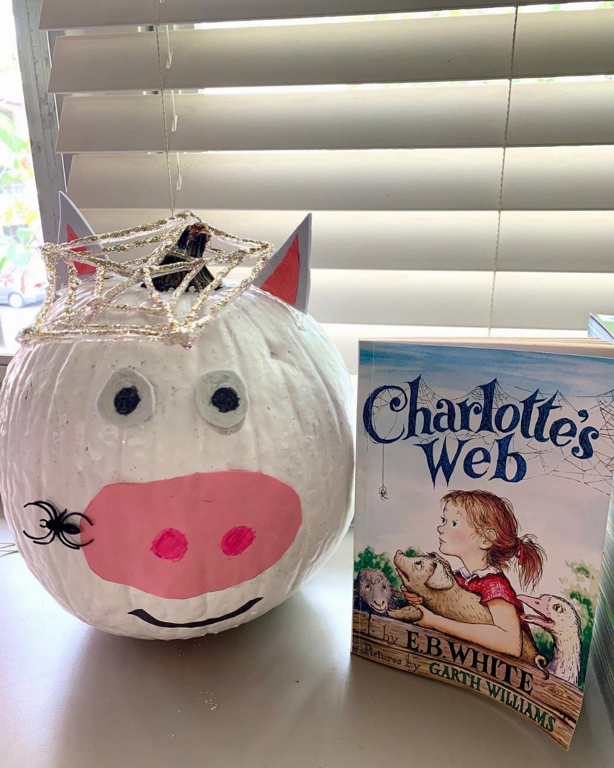 White pumpkin decorated as a pig next to the book Charlotte's Web