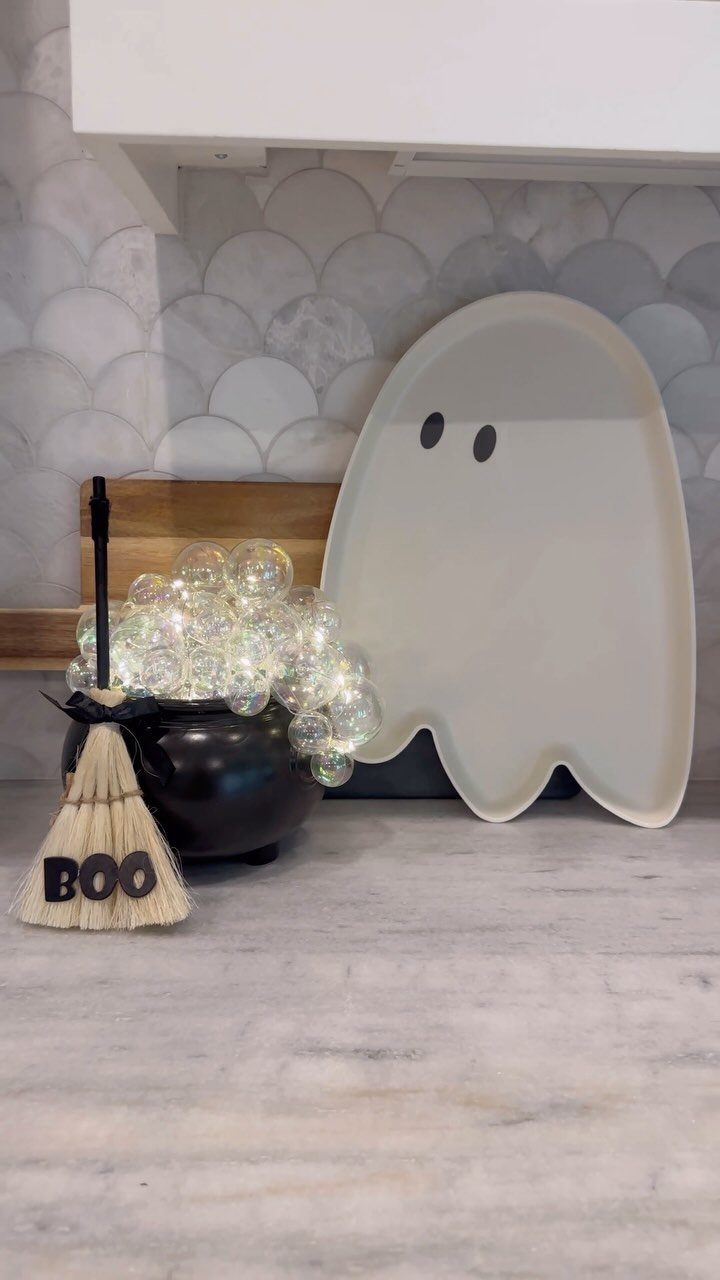 Black cauldron overflowing with glowing clear bubbles next to a ghost platter.