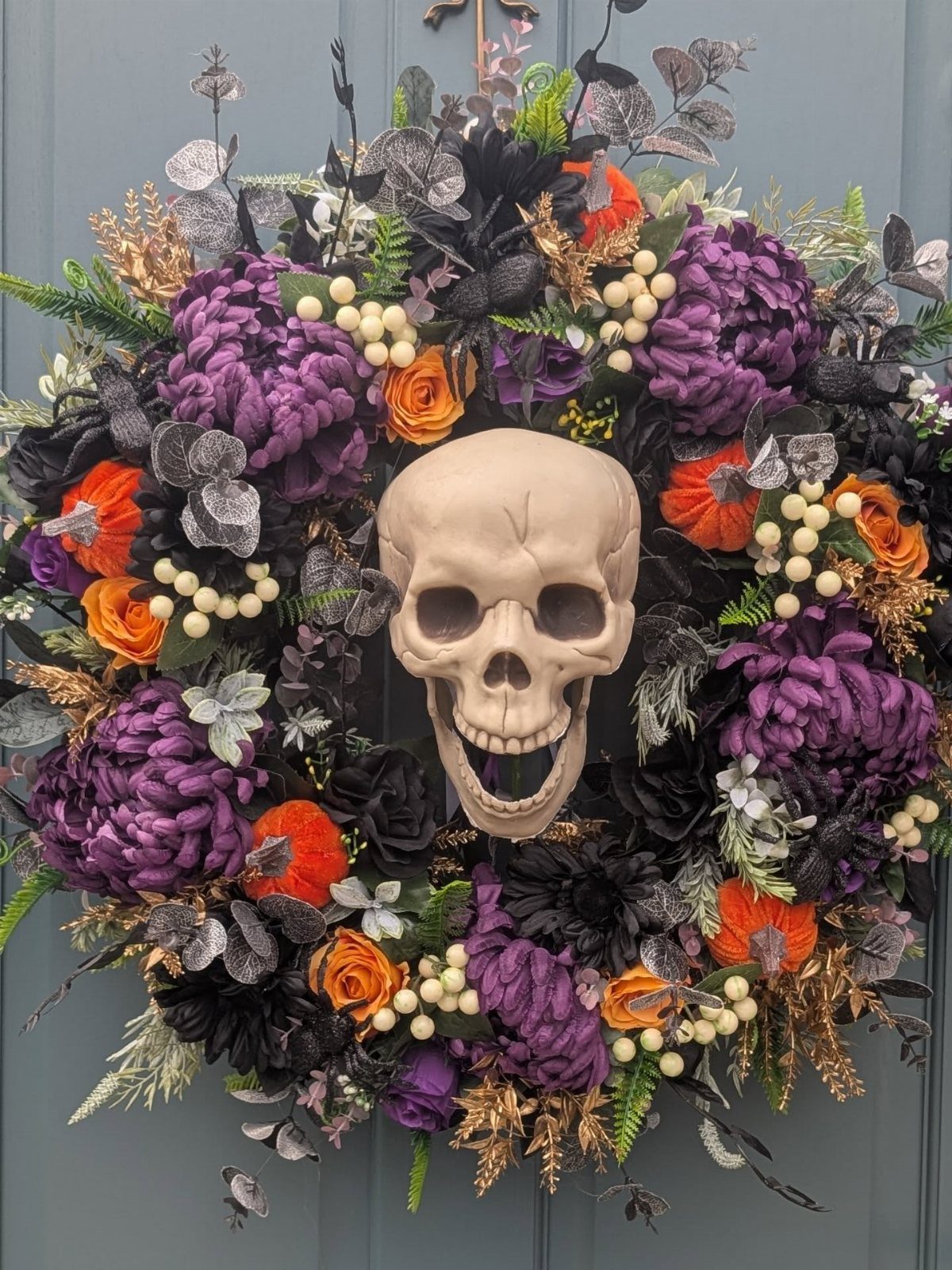 Halloween wreath with a central skull, purple and orange flowers, and silver foliage.